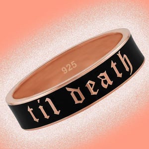 May include: A rose gold ring with a black enamel band. The words "til death" are inscribed in gothic lettering around the band. The inside of the ring is stamped with "925".