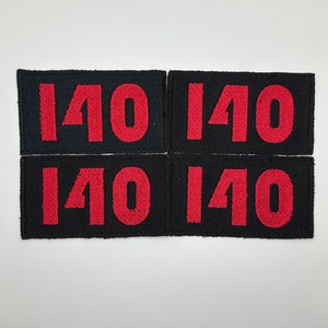 May include: Four black fabric patches with the number 140 in red embroidered on each.