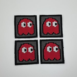 Può includere: Quattro toppe ricamate rosse da stirare raffiguranti un fantasma pixelato con occhi bianchi. Le toppe sono su uno sfondo grigio con un bordo nero.