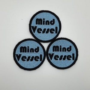 May include: Three blue and black round embroidered patches with the text "Mind Vessel" in black.