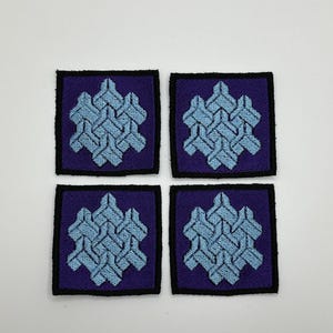 May include: Four square embroidered patches with a light blue geometric design on a dark purple background. The patches have a black border.
