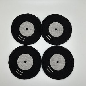 May include: Four black and white vinyl record-shaped patches. The patches are embroidered with a white circle in the center and two white lines on the outer edge.