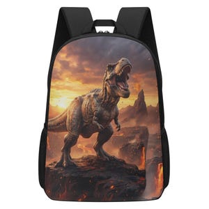 May include: A black backpack featuring a large, detailed graphic print of a Tyrannosaurus Rex standing on a rocky cliff. The background depicts a dramatic volcanic landscape with glowing lava, dark mountains, and a fiery orange sunset sky.