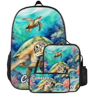 Puede incluir: Un conjunto de mochila, bolsa de almuerzo y estuche con un diseño de acuarela de tortugas marinas nadando en una escena oceánica. El conjunto es predominantemente turquesa y beige, con detalles de coral y peces. El nombre "Cameron" está impreso.