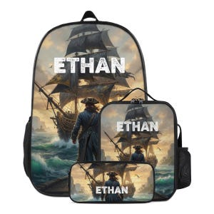 Puede incluir: Un conjunto de mochila, bolsa de almuerzo y estuche con un gráfico impreso de un barco pirata en el océano y una persona con sombrero pirata en un muelle. El nombre ETHAN está impreso en letras mayúsculas blancas en cada artículo.