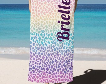 Puede incluir: Una toalla de playa con un patrón de degradado arcoíris y estampado de leopardo. La toalla tiene el nombre "Brielle" impreso en morado.