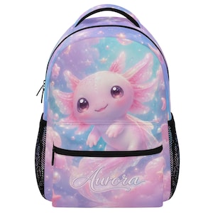 Puede incluir: Una mochila con fondo azul y morado pastel que presenta una ilustración central de un ajolote rosa rodeado de estrellas y nubes. El nombre Aurora está impreso en una fuente cursiva blanca en el bolsillo frontal, que tiene cremalleras negras.