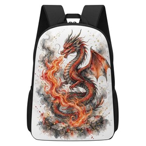 Peut inclure: Un sac à dos noir avec un panneau avant blanc illustré d'un dragon rouge à l'aquarelle crachant des flammes orange et jaunes. Le dragon est posé sur des rochers gris, entouré de fumée sombre et de petits accents d'étoiles dorées.