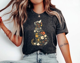 May include: Dark gray t-shirt featuring a floral cat design. The cat silhouette is filled with colorful flowers in shades of yellow, orange, and white. The shirt is a casual wear item.