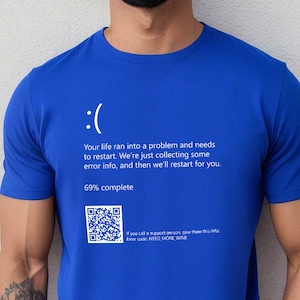 May include: Bright blue t-shirt with a computer error screen design. It features a sad face, text about restarting, and a QR code. The text includes "69% complete" and "Error code: NEED_MORE_WINE". A humorous and geeky design.