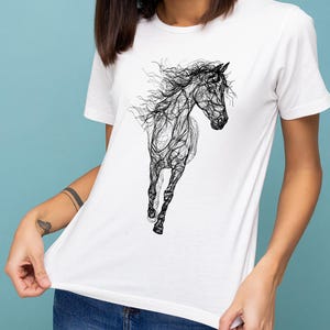 May include: White t-shirt featuring a black line art illustration of a running horse. The design showcases the horse's form with flowing lines, creating a dynamic and artistic representation. The shirt is a classic crew neck style.