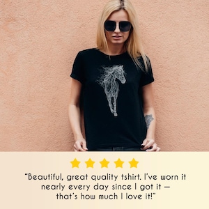 May include: Black t-shirt featuring a white, stylized horse graphic. The design depicts a running horse with a flowing mane and tail. The shirt is worn by a person wearing sunglasses.