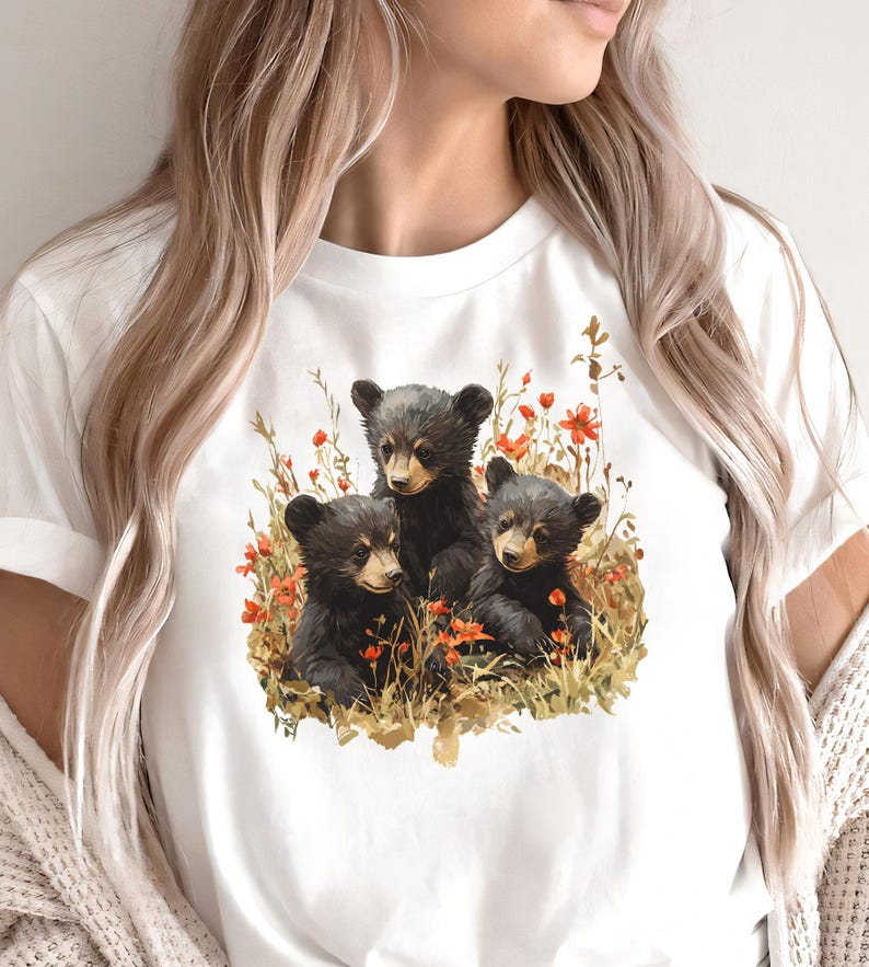 May include: White t-shirt with a graphic of three black bear cubs sitting in a field of flowers.