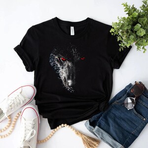 Puede incluir: Camiseta negra con un gr&aacute;fico de la cara de un lobo con ojos rojos. La cara del lobo est&aacute; en el centro de la camiseta y est&aacute; rodeada de un fondo negro.