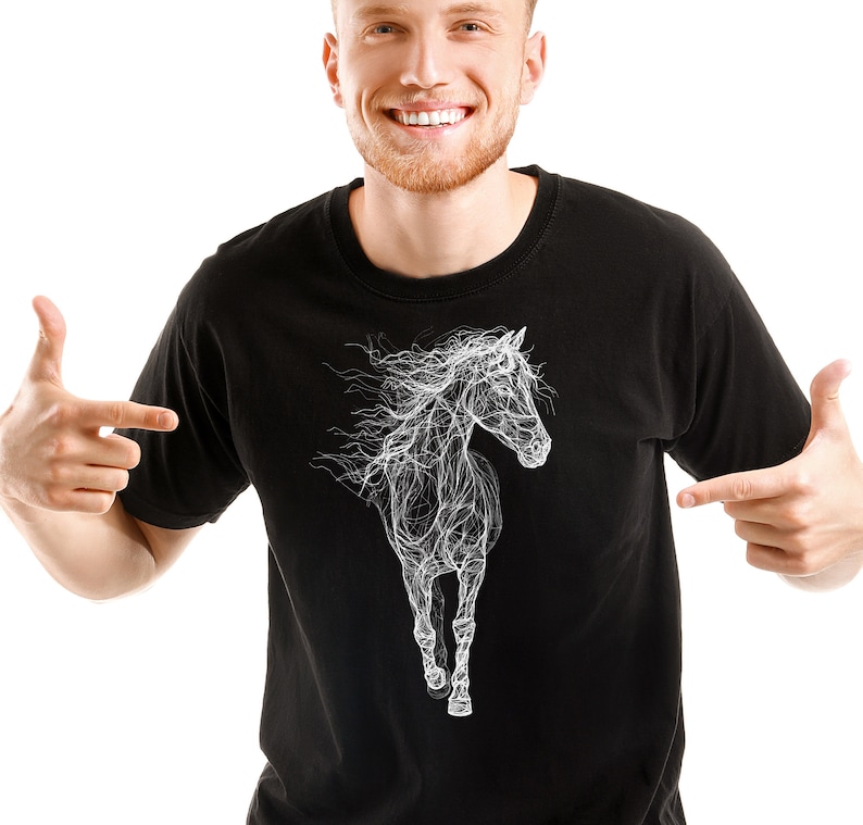 May include: Black t-shirt featuring a white, stylized illustration of a running horse. The horse design has a flowing, almost ethereal quality. The shirt is a classic crew neck style.