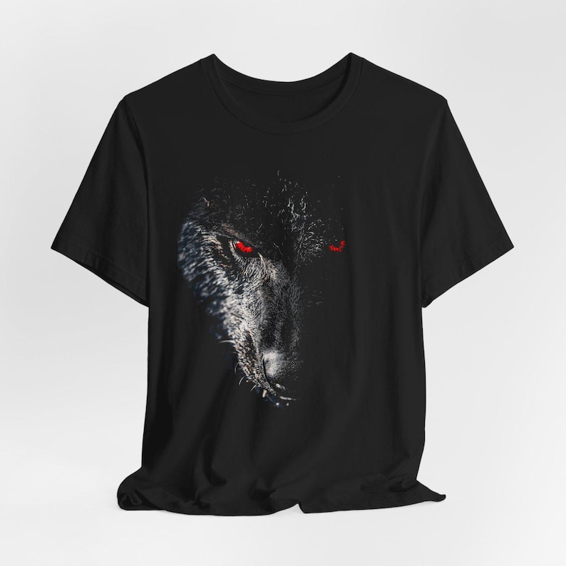 Puede incluir: Camiseta negra con un estampado gr&aacute;fico de la cara de un lobo con ojos rojos.