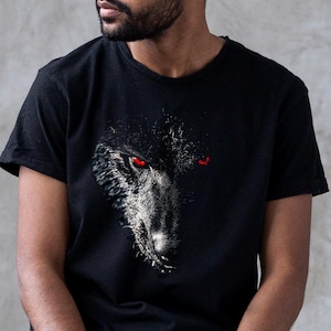 Puede incluir: Una camiseta negra con un gr&aacute;fico de la cara de un lobo. El lobo tiene ojos rojos y una expresi&oacute;n amenazante.