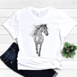 May include: White t-shirt featuring a black line art illustration of a running horse. The horse's mane and tail flow in the wind. The shirt is paired with dark blue jeans.