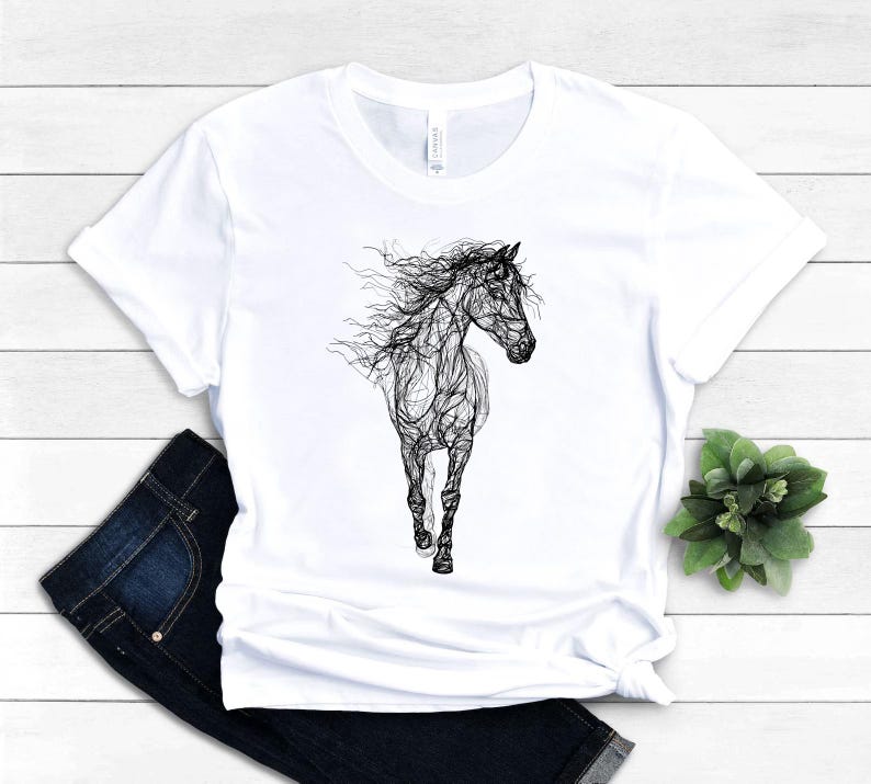 May include: White t-shirt featuring a black line art illustration of a running horse. The horse's mane and tail flow in the wind. The shirt is paired with dark blue jeans.
