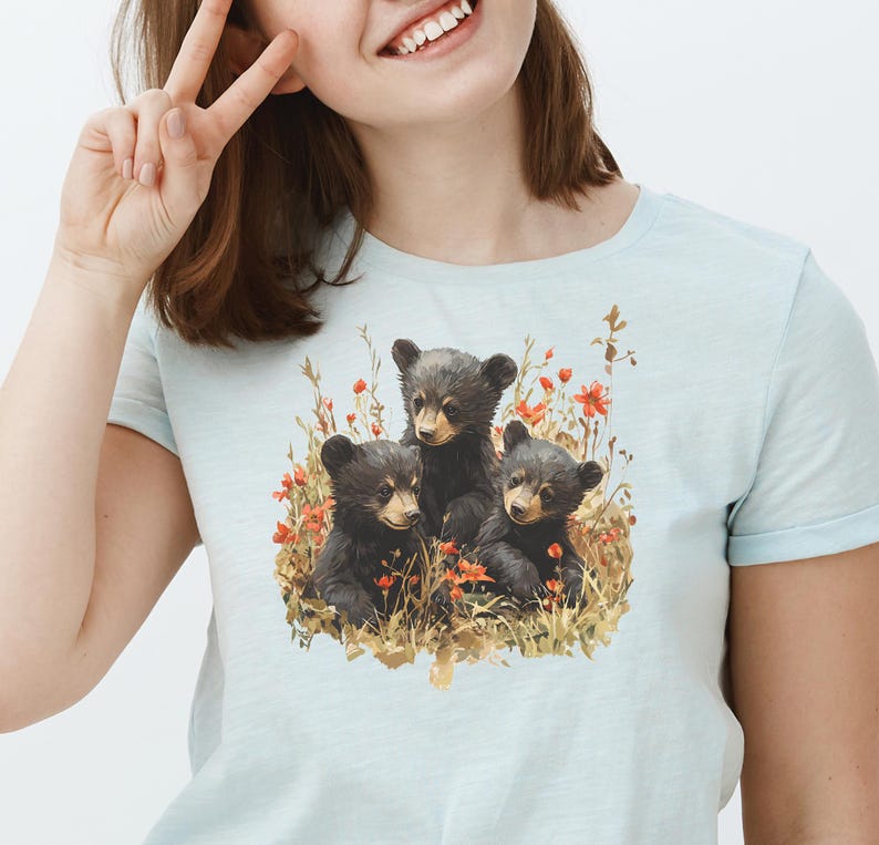 May include: A light blue t-shirt with a graphic of three black bear cubs surrounded by red flowers and green foliage.