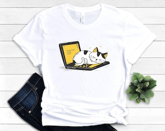 Op de afbeelding: Wit T-shirt met een afbeelding van een kat die slaapt op een laptop. Het laptopscherm toont "important work stuff".