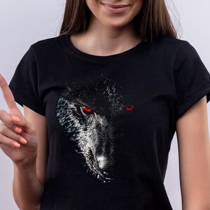 Puede incluir: Camiseta negra con un estampado gr&aacute;fico de la cara de un lobo con ojos rojos.