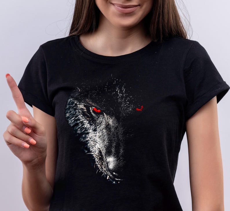 Puede incluir: Camiseta negra con un estampado gr&aacute;fico de la cara de un lobo con ojos rojos.