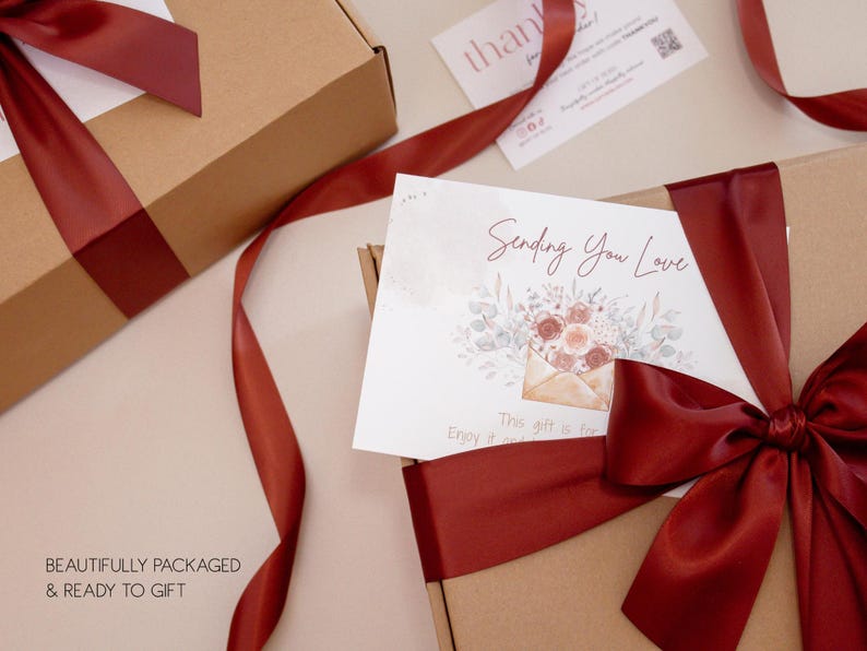 May include: Two brown gift boxes with burgundy ribbon and bows. One box has a card that says "Sending You Love" with a floral design. The text "BEAUTIFULLY PACKAGED & READY TO GIFT" is at the bottom.