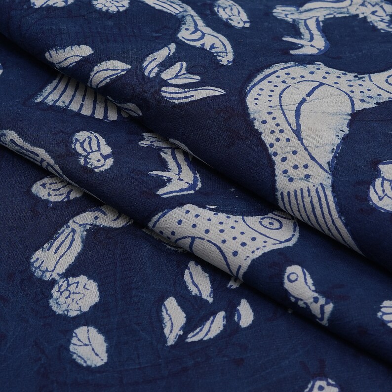 Peut inclure: Tissu bleu indigo avec un motif imprim&eacute; blanc de poissons stylis&eacute;s et de feuilles. Le tissu a une texture douce.