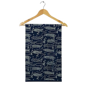 May include: A navy blue textile with a repeating pattern of white fish and bubbles, displayed on a wooden hanger. The fish are stylized with various designs, creating a nautical theme. The fabric is rectangular and appears to be a towel or decorative cloth.