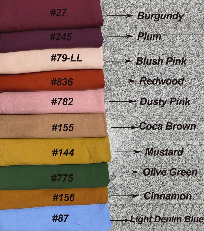 Puede incluir: Una pila de muestras de tela en varios colores, incluyendo borgo&ntilde;a, ciruela, rosa rubor, secuoya, rosa polvoriento, marr&oacute;n coca, mostaza, verde oliva, canela y azul denim claro. Cada muestra est&aacute; etiquetada con un nombre de color y un n&uacute;mero.