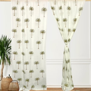 Könnte beinhalten: Ein Paar weiße, durchsichtige Vorhänge mit grünem Palmenbaumdruck. Die Vorhänge sind an einer weißen Stange aufgehängt und mit einem Knoten zurückgebunden.