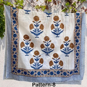 K&ouml;nnte beinhalten: Wei&szlig;er Baumwollstoff mit einem blauen und braunen Blumenmuster. Der Stoff hat einen Rand mit einem blauen und braunen Streifenmuster. Der Stoff ist mit "Pattern-8" gekennzeichnet.