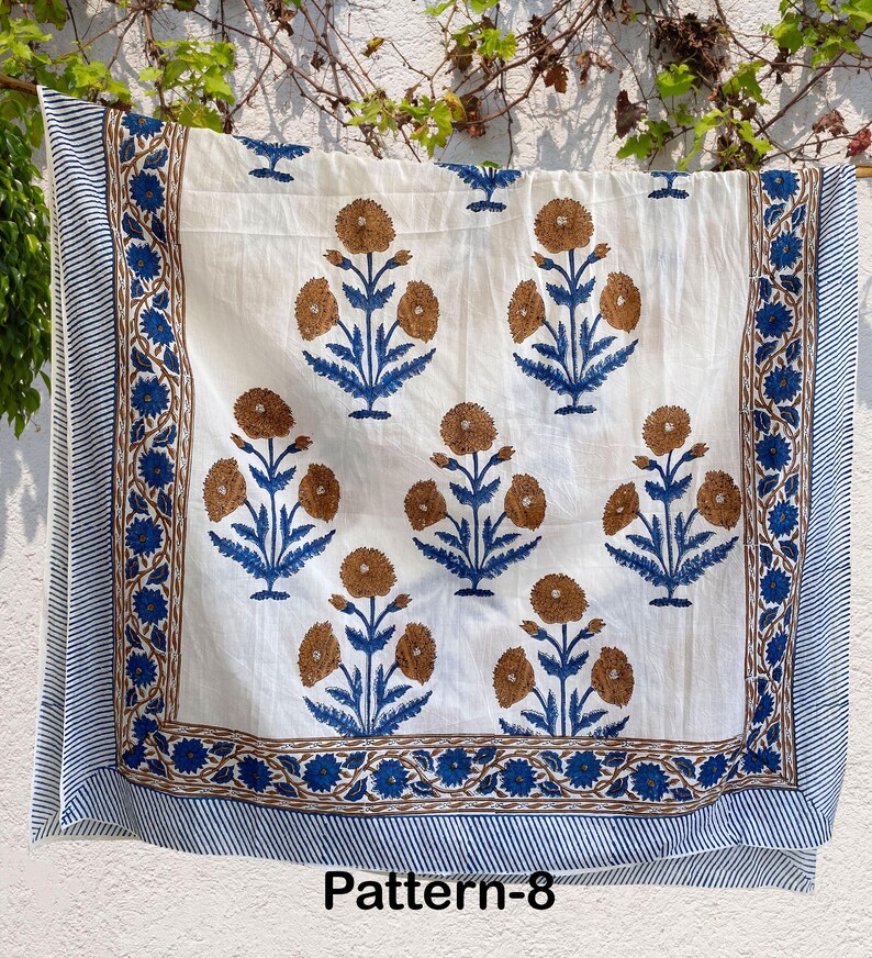 K&ouml;nnte beinhalten: Wei&szlig;er Baumwollstoff mit einem blauen und braunen Blumenmuster. Der Stoff hat einen Rand mit einem blauen und braunen Streifenmuster. Der Stoff ist mit "Pattern-8" gekennzeichnet.