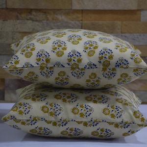 Pode incluir: Duas almofadas de cor creme com um padr&atilde;o floral em tons de amarelo e azul.