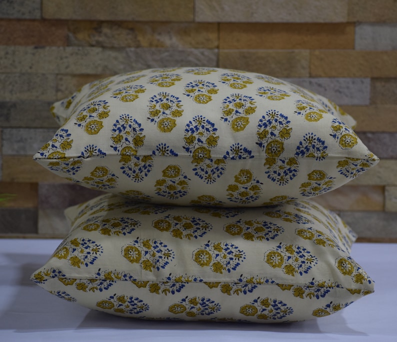 Pode incluir: Duas almofadas de cor creme com um padr&atilde;o floral em tons de amarelo e azul.