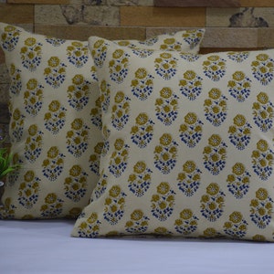 Pode incluir: Duas almofadas de cor creme com um padr&atilde;o floral em tons de amarelo e azul. As almofadas s&atilde;o feitas de um tecido de algod&atilde;o macio e t&ecirc;m um brilho sutil.