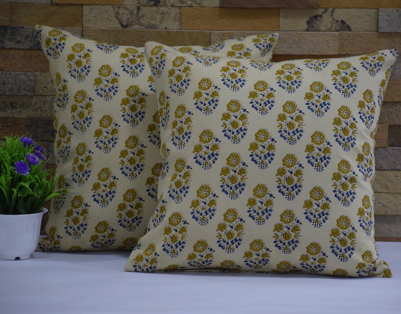 Pode incluir: Duas almofadas de cor creme com um padr&atilde;o floral em tons de amarelo e azul. As almofadas s&atilde;o feitas de um tecido de algod&atilde;o macio e t&ecirc;m um brilho sutil.