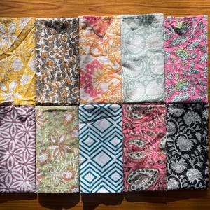 Può includere: Set di dieci tovaglioli in tessuto con vari motivi floreali e geometrici. I tovaglioli sono in tonalità di rosa, blu, verde, giallo e marrone.