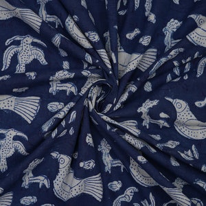 Peut inclure: Tissu en coton bleu indigo avec un motif imprim&eacute; blanc d'oiseaux et de poissons stylis&eacute;s. Le tissu est pli&eacute; et drap&eacute;, montrant le motif.