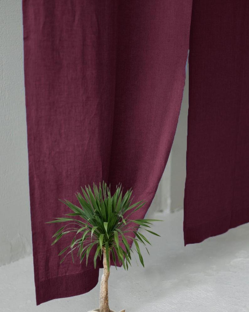 Pode incluir: Um par de cortinas em tom bord&ocirc; profundo feitas de um tecido texturizado que pende verticalmente. As cortinas apresentam um design simples de corte reto com uma trama vis&iacute;vel, criando um efeito de bloco de cor s&oacute;lida de cima a baixo.