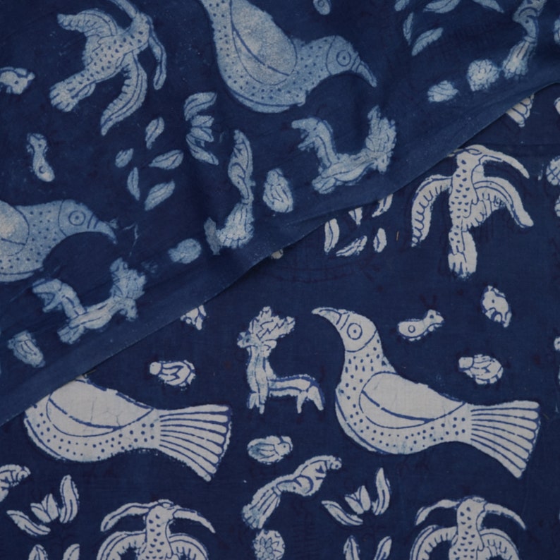 Peut inclure: Tissu bleu indigo avec un motif blanc d'oiseaux et de feuilles stylis&eacute;s. Le tissu est pli&eacute; en deux, montrant le motif des deux c&ocirc;t&eacute;s.