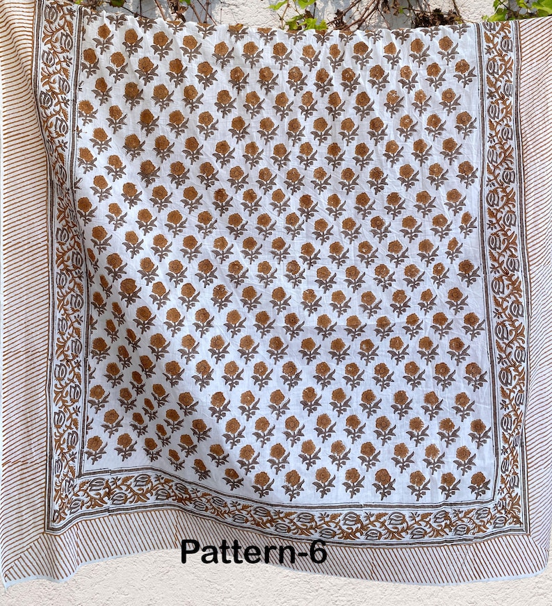 K&ouml;nnte beinhalten: Wei&szlig;er Stoff mit braunem Blumenmuster. Der Stoff hat einen Rand mit einem gestreiften Muster. Der Stoff ist mit "Pattern-6" gekennzeichnet.