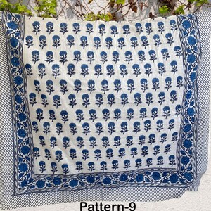 K&ouml;nnte beinhalten: Wei&szlig;er Baumwollstoff mit einem blauen Blumenmuster. Der Stoff hat einen Rand mit einem blau-wei&szlig; gestreiften Muster. Der Stoff ist mit "Pattern-9" gekennzeichnet.