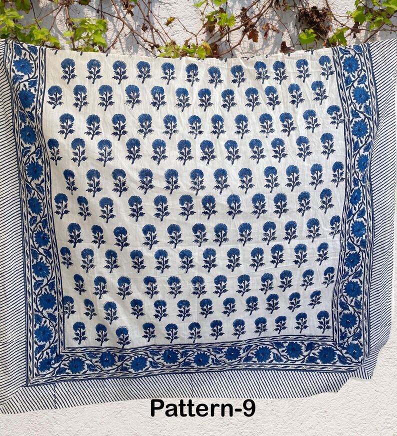 K&ouml;nnte beinhalten: Wei&szlig;er Baumwollstoff mit einem blauen Blumenmuster. Der Stoff hat einen Rand mit einem blau-wei&szlig; gestreiften Muster. Der Stoff ist mit "Pattern-9" gekennzeichnet.