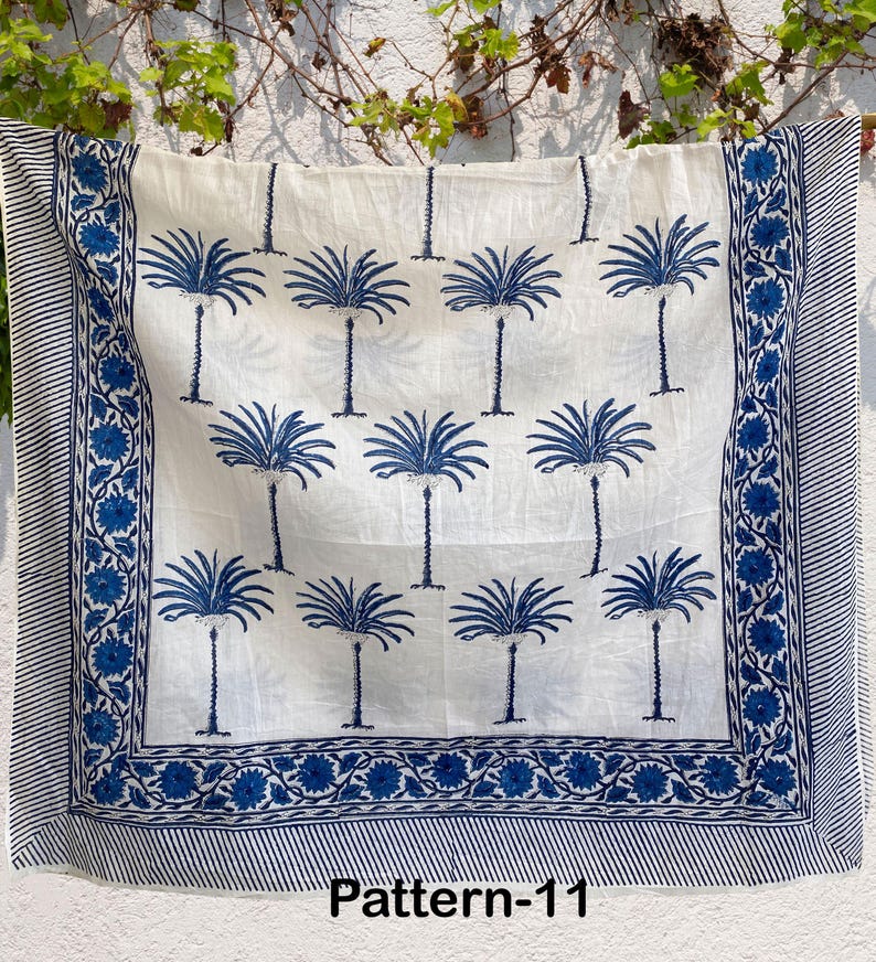 K&ouml;nnte beinhalten: Ein wei&szlig;er Baumwollstoff mit einem blauen und wei&szlig;en Palmenbaumdruck. Der Stoff hat einen blauen Rand mit einem floralen Muster. Der Text "Pattern-11" ist unten auf dem Stoff gedruckt.