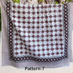 K&ouml;nnte beinhalten: Wei&szlig;er Baumwollstoff mit braunem geometrischem Muster. Der Stoff hat einen Rand mit einem sich wiederholenden Muster aus Kreisen und Streifen. Der Stoff ist mit "Pattern-7" gekennzeichnet.