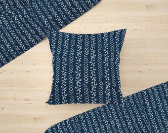 May include: A square navy blue pillow with a white leaf and diamond pattern. Two fabric pieces with the same pattern are arranged around the pillow on a light wood surface. The pillow is approximately 18 inches square.
