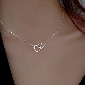 May include: A silver necklace with a delicate chain and a double heart pendant.