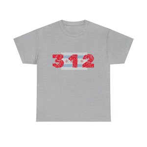 Puede incluir: Camiseta gris con el número "312" en fuente roja desgastada. El diseño incluye una franja horizontal en rojo, blanco y azul, que representa el código de área y la bandera de Chicago.